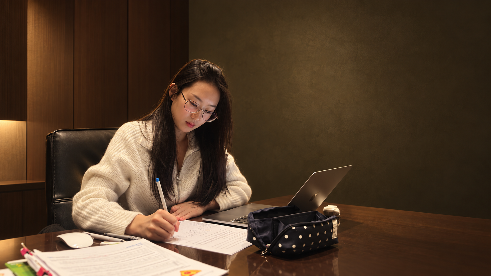 Grace studying and writing notes beside her laptop