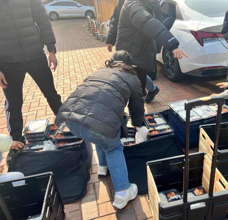 Volunteers preparing lunch boxes for older adults in a jjokbang village
