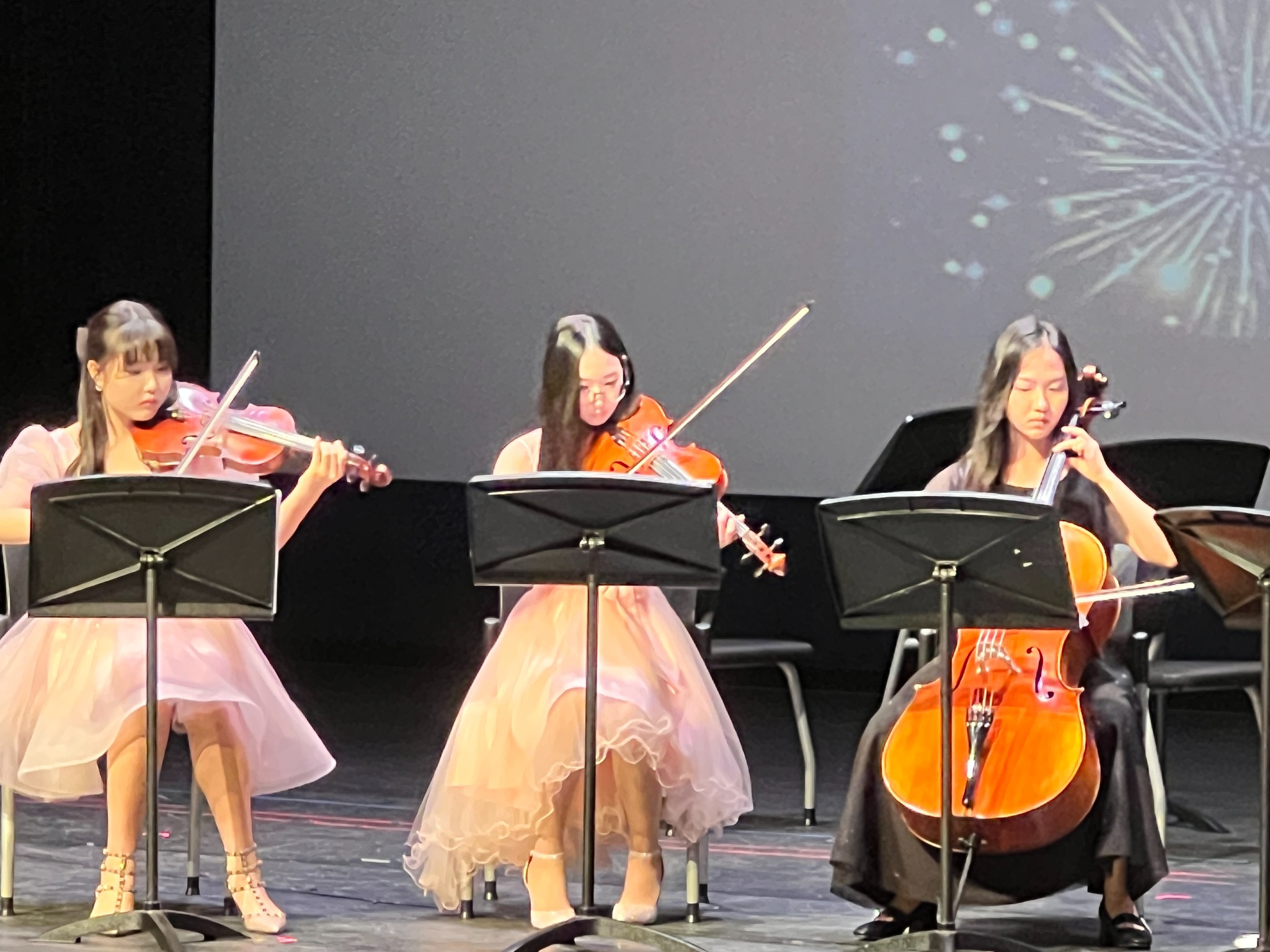 Three student musicians performing together on stage