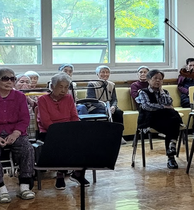 Residents listening to a student music performance