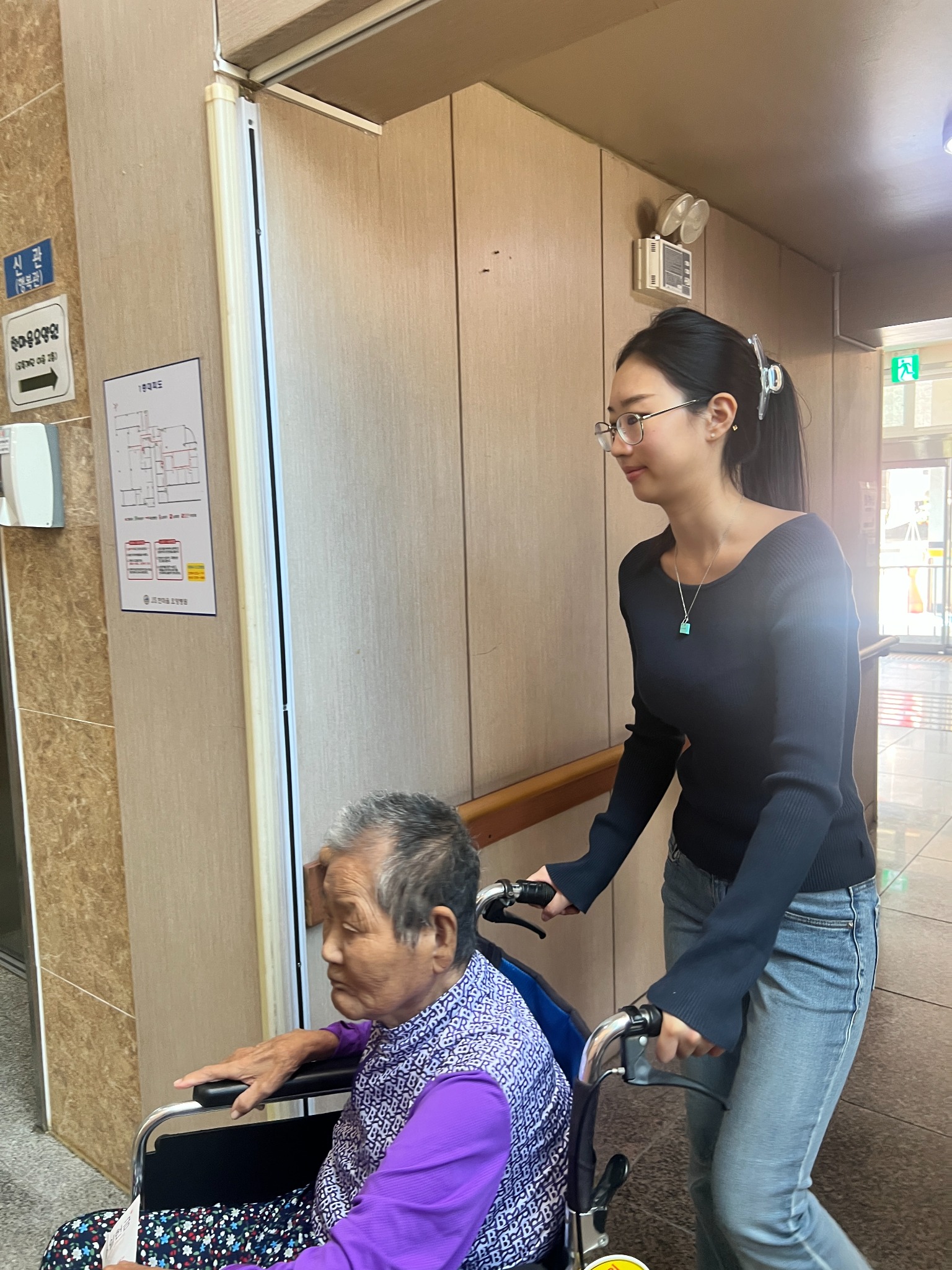 Grace accompanying a resident in a wheelchair